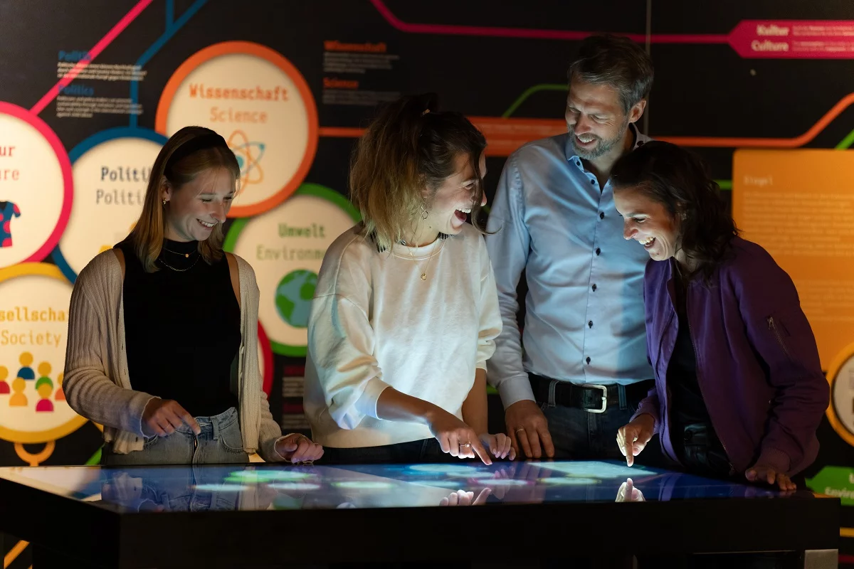 Besucher am Multifunktionstisch in der Ausstellung Weltreise des Kakaos